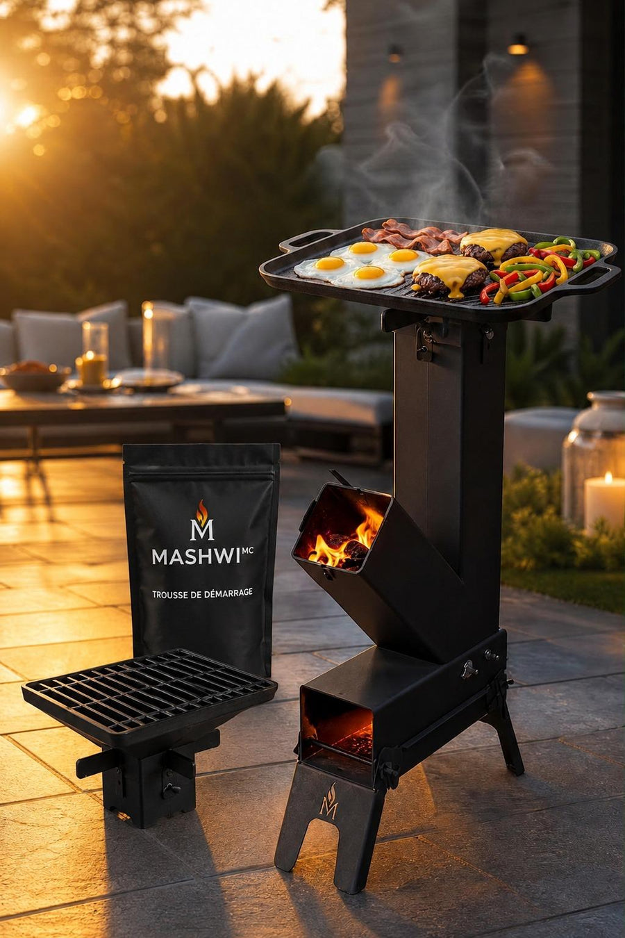L’Ensemble de Base MASHWIᴹᶜ sur une terrasse au coucher du soleil : le poêle-fusée avec sa plancha garnie, la trousse de démarrage et le gril montable.